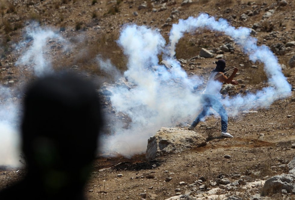 A Palestinian protester uses a slingshot to throw back a tear gas canister during clashes with Israeli security forces on August 28, 2015 in the West Bank village of Nabi Saleh (AFP Photo / Abbas Momani) A Palestinian protester uses a slingshot to throw back a tear gas canister during clashes with Israeli security forces on August 28, 2015 in the West Bank village of Nabi Saleh (AFP Photo / Abbas Momani)