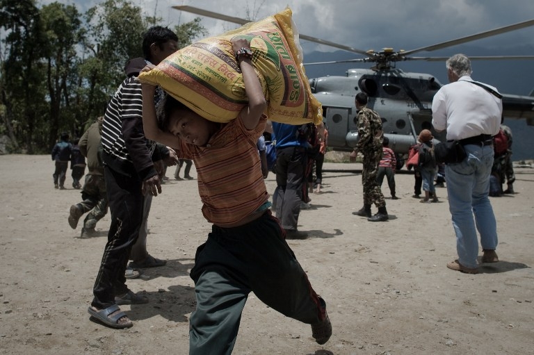 A boy carries a sack of rice from an Indian Air Force Helicopter in the village of Barpak in north-central Nepal on May 4, 2015 A boy carries a sack of rice from an Indian Air Force Helicopter in the village of Barpak in north-central Nepal on May 4, 2015