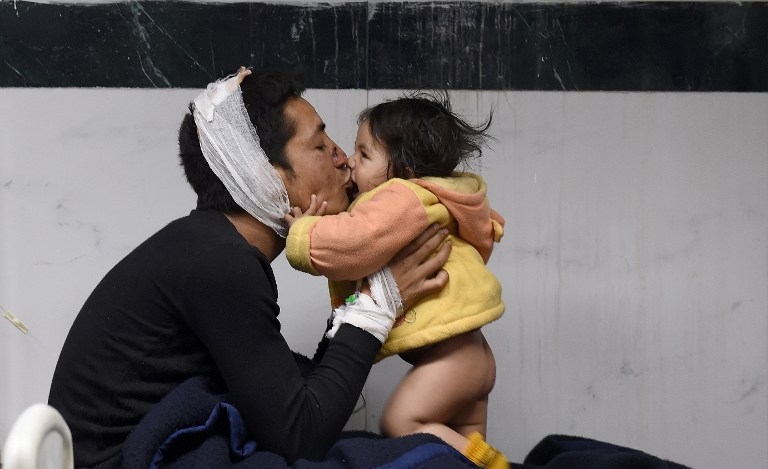 Nepalese man Suresh Parihar plays with his 8-month-old daughter Sandhaya as he is treated at a hospital in Kathmandu on April 26, 2015 Nepalese man Suresh Parihar plays with his 8-month-old daughter Sandhaya as he is treated at a hospital in Kathmandu on April 26, 2015
