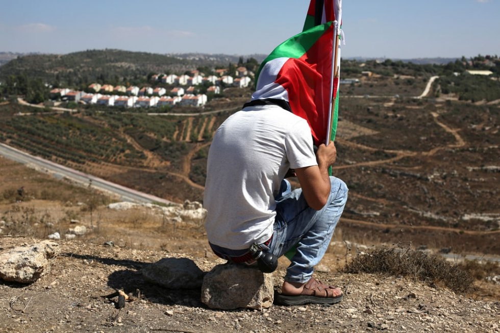 A Palestinian protester sits holding a national flag after a march against Palestinian land confiscation on August 28, 2015 in the West Bank village of Nabi Saleh (AFP Photo / Abbas Momani) A Palestinian protester sits holding a national flag after a march against Palestinian land confiscation on August 28, 2015 in the West Bank village of Nabi Saleh (AFP Photo / Abbas Momani)