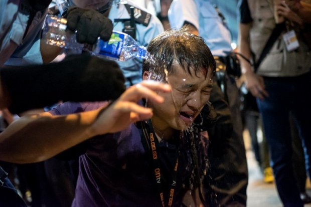 Police pour water on a local Hong Kong journalist after he was pepper sprayed in the Mongkok district of Hong Kong on October 17, 2014 (AFP Photo / Alex Ogle) Police pour water on a local Hong Kong journalist after he was pepper sprayed in the Mongkok district of Hong Kong on October 17, 2014 (AFP Photo / Alex Ogle)