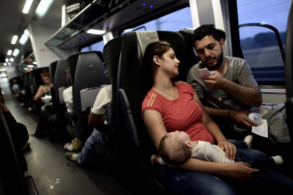Iraqi refugees Ahmad (R) ,27 and Alia ,26, holding their four months old baby Adam, try to communicate with their family as they travel by train from Austria to Germany, on September 3 (AFP Photo / Aris Messinis) Iraqi refugees Ahmad (R) ,27 and Alia ,26, holding their four months old baby Adam, try to communicate with their family as they travel by train from Austria to Germany, on September 3 (AFP Photo / Aris Messinis)