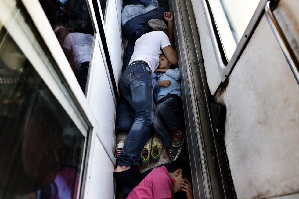"Syrian refugees and migrants sleep on the floor of a carriage on a train from Macedonia to the Serbian border, on August 30, 2015 "Syrian refugees and migrants sleep on the floor of a carriage on a train from Macedonia to the Serbian border, on August 30, 2015