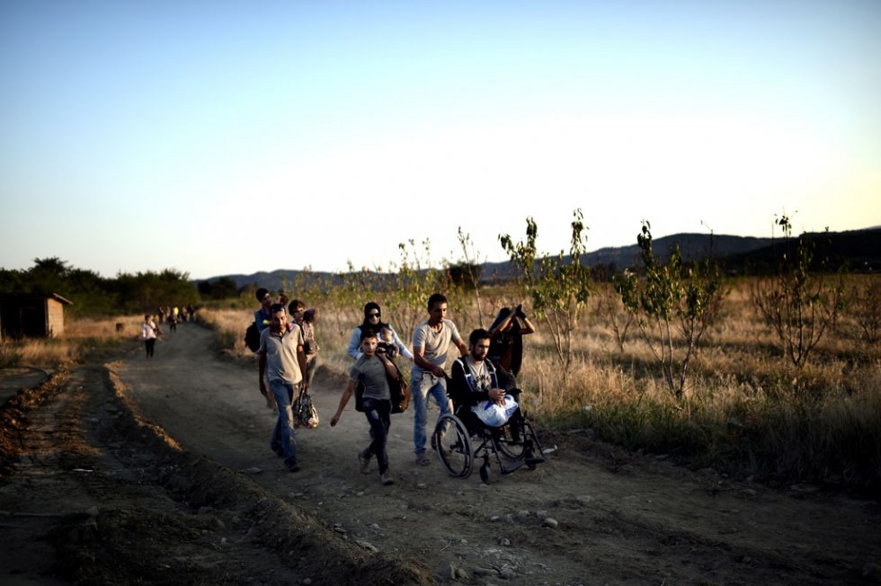 A Syrian man who lost his legs in a shelling near Damascus is helped by other migrants as they cross the border from Greece to Macedonia on August 29, 2015 A Syrian man who lost his legs in a shelling near Damascus is helped by other migrants as they cross the border from Greece to Macedonia on August 29, 2015
