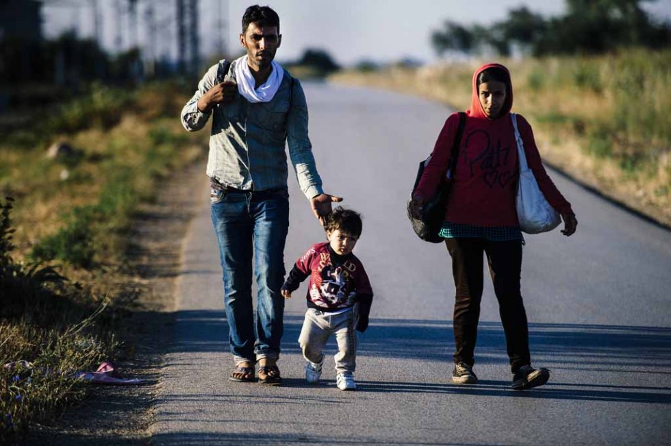 A migrant family walks on a road near Presevo on July 15, 2015 A migrant family walks on a road near Presevo on July 15, 2015