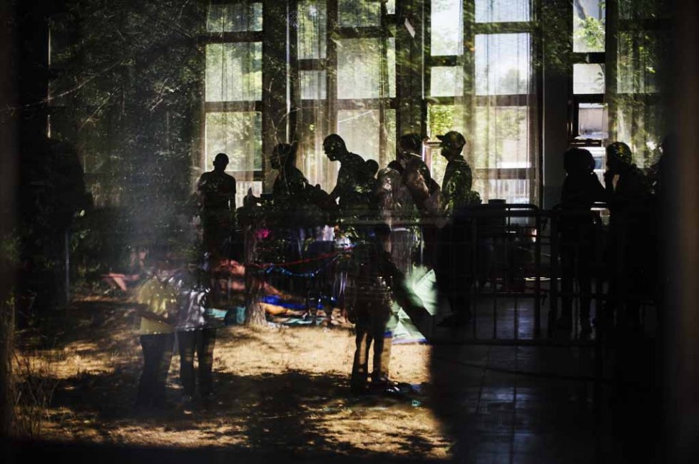 Migrants are pictured through a window as they wait for papers at a centre in Presevo on July 15, 2015 Migrants are pictured through a window as they wait for papers at a centre in Presevo on July 15, 2015