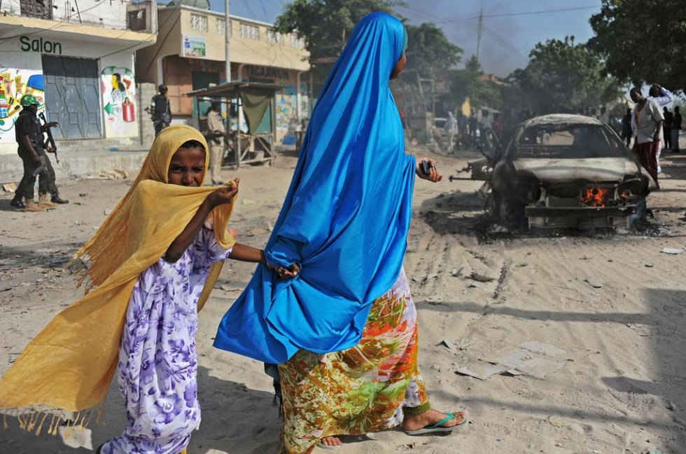 A mother and a child walk past the wreckage of a car bomb in the Wardhigley District, south of Mogadishu, on February 27, 2015 A mother and a child walk past the wreckage of a car bomb in the Wardhigley District, south of Mogadishu, on February 27, 2015