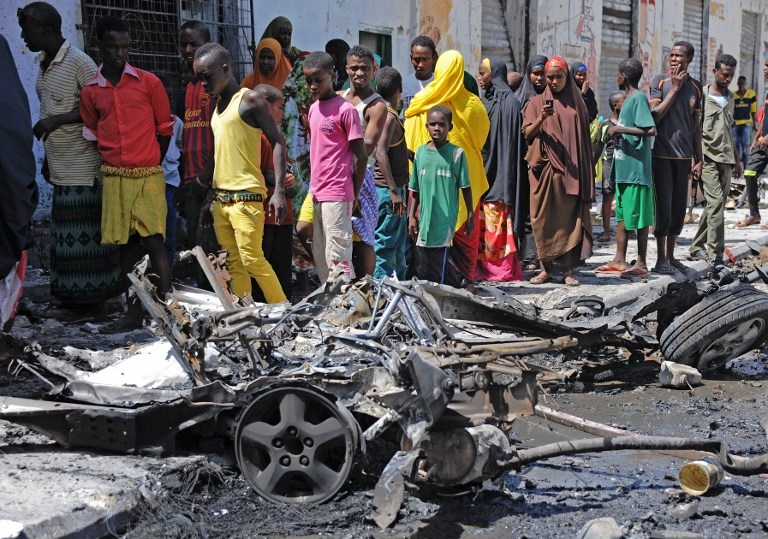 Bystanders look at the wreckage of a car bomb attack that killed three people in Mogadishu on April 21, 2015 Bystanders look at the wreckage of a car bomb attack that killed three people in Mogadishu on April 21, 2015