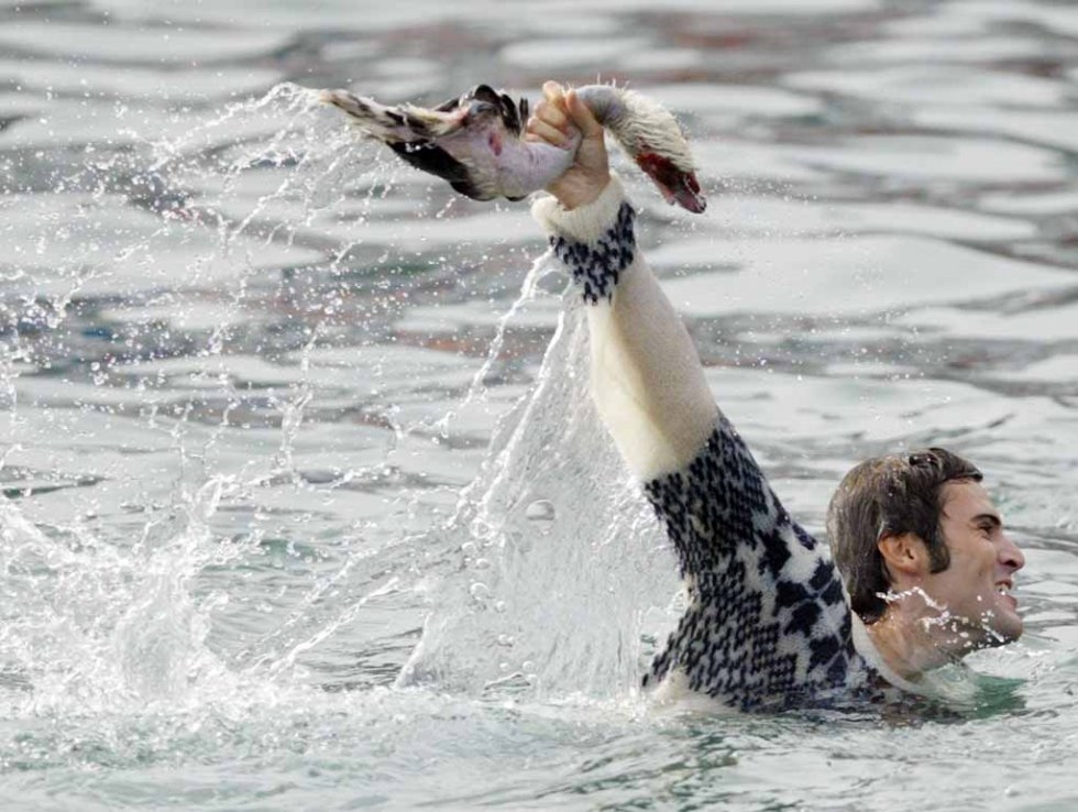 Victory -- a man celebrates ripping the head and neck off a dead goose. Victory -- a man celebrates ripping the head and neck off a dead goose.