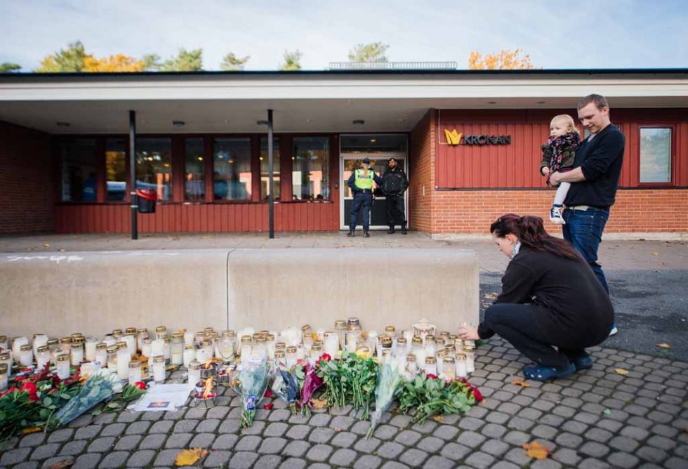 A woman lights a candle outside the school after the attack. A woman lights a candle outside the school after the attack.