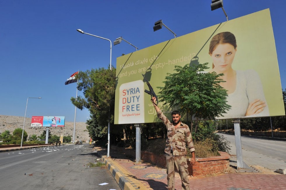 A Syrian rebel poses in front of a sign at the Bab al-Hawa border crossing with Syria. July, 2012. A Syrian rebel poses in front of a sign at the Bab al-Hawa border crossing with Syria. July, 2012.