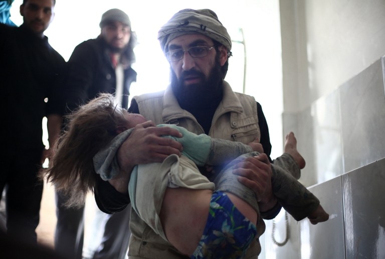 A man carries a wounded child at a makeshift clinic in Douma, Syria on February 5, 2015 A man carries a wounded child at a makeshift clinic in Douma, Syria on February 5, 2015