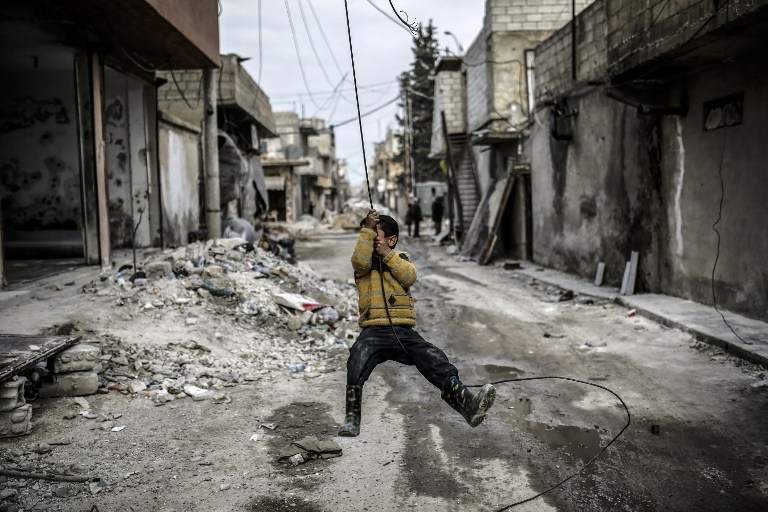A Kurdish boy plays with a disused power cable in Kobane on March 24, 2015 A Kurdish boy plays with a disused power cable in Kobane on March 24, 2015