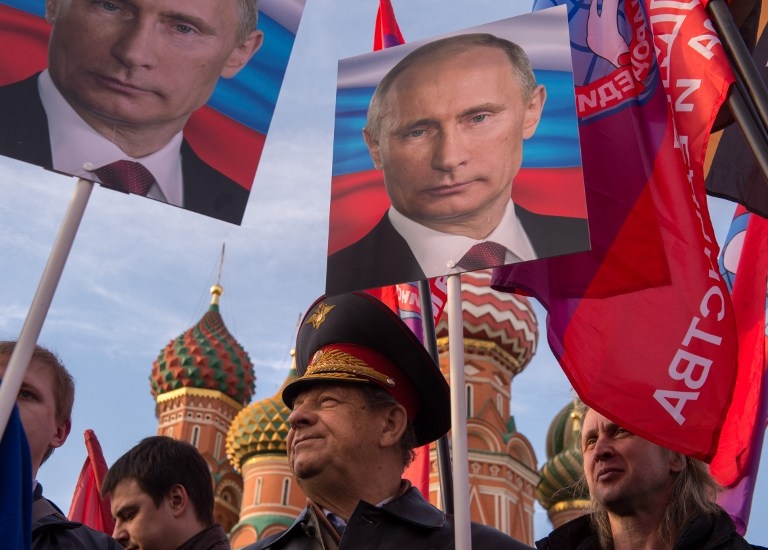 People hold placards depicting Russia's President Vladimir Putin at a rally in Moscow on March 18, 2015, to mark one year since the annexation of Crimea People hold placards depicting Russia's President Vladimir Putin at a rally in Moscow on March 18, 2015, to mark one year since the annexation of Crimea