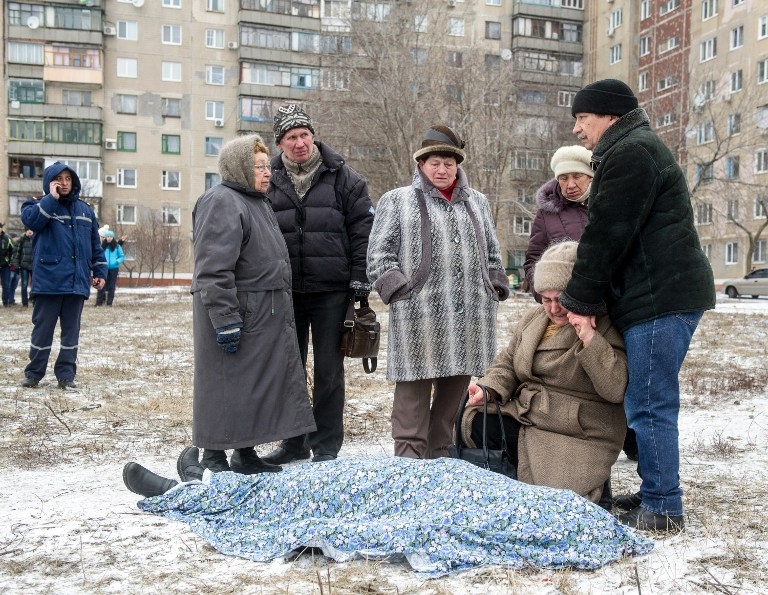 Relatives stand beside the body of a victim of a shelling in Kramotorsk on February 10, 2015 Relatives stand beside the body of a victim of a shelling in Kramotorsk on February 10, 2015