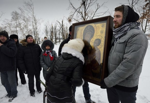 A woman kisses an icon of Our Lady of Tikhvin at the Savur-Mogyla memorial A woman kisses an icon of Our Lady of Tikhvin at the Savur-Mogyla memorial