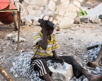 A young boy crushes stones at a quarry in Ouagadougou where adults and children work on December 21, 2015.