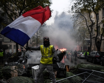 demonstrator holds a French flag during a protest of Yellow vests (Gilets jaunes) against rising oil prices and living costs, on December 1, 2018 in Paris. - Speaking at the Paris police's command centre, French Prime Minister said 36,000 people were prot