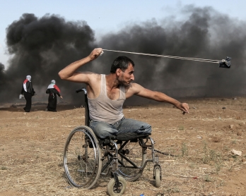 Palestinian Saber al-Ashkar, 29, hurls rocks during clashes with Israeli forces along the border with the Gaza strip, east of Gaza City, on May 11, 2018, as Palestinians demonstrate for the right to return to their historic homeland in what is now Israel.