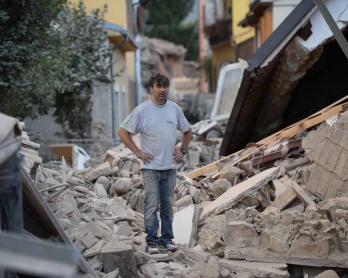 A man stands on a damaged home after a strong earthquake hit Amatrice on August 24, 2016.