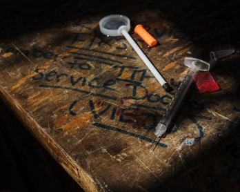 A needle, narcotics bag, and blood stain are seen with a reminder to tip the Service Docs at a heroin encampment in the Kensington neighborhood of Philadelphia, Pennsylvania, on April 10, 2017