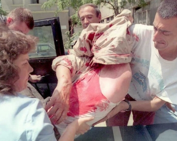 A journalist (R) and a passer-by rescue a badly injured bus driver after his coach was hit by a mortar in the center of Sarajevo on June 15, 1995 (AFP Photo / Anja Niedringhaus)